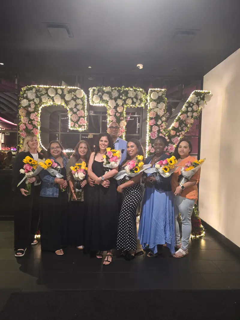 AMP team members holding sunflower bouquets at a team celebration dinner